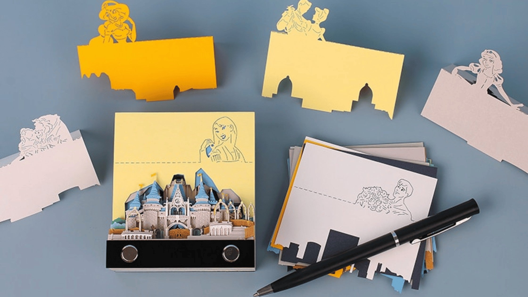 Pages illustrées détachées autour du bloc-notes Château Enchanté